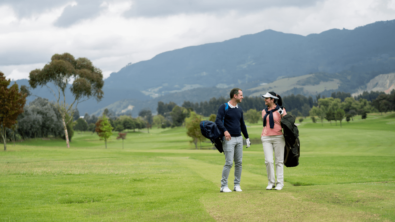 man en vrouw lopen over de golfbaan met draagtas
