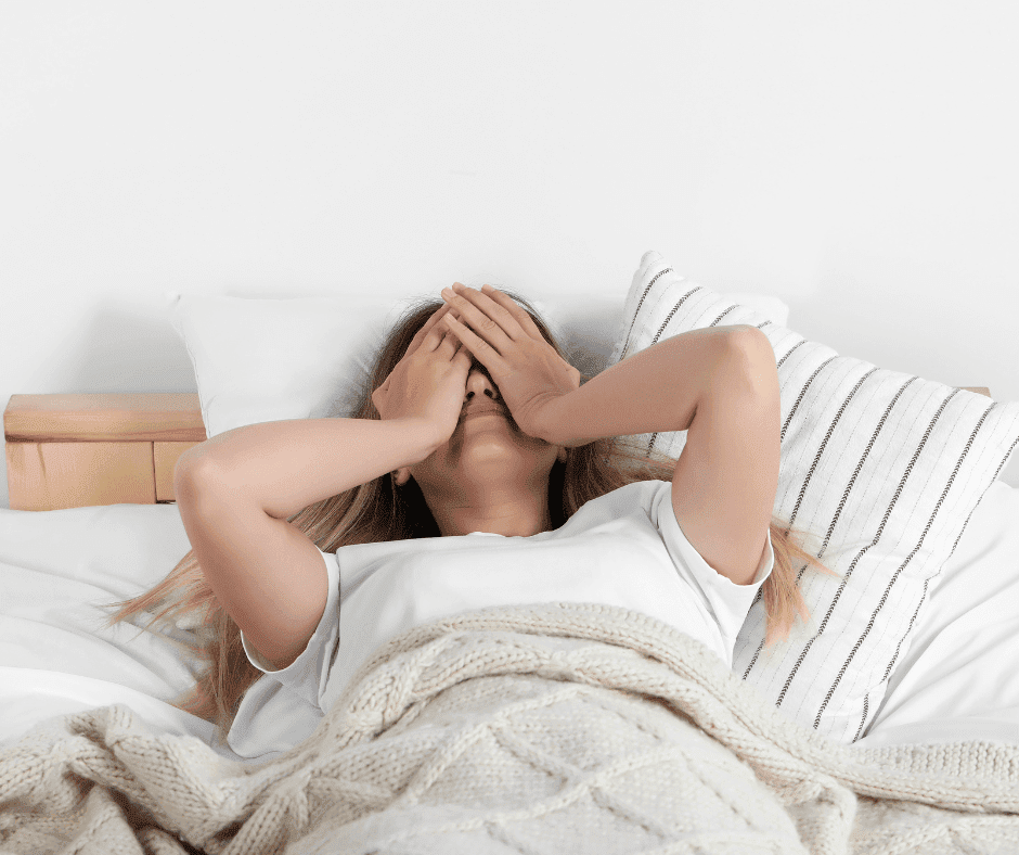 vrouw ligt in bed met handen voor haar hoofd. Ze heeft last van RLS